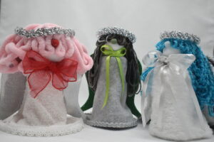 Three handmade angel gnomes from the Angels Among Us collection featuring Angelica, Angelina, and Angela in blue, pink, gray, green, and white decorative designs.