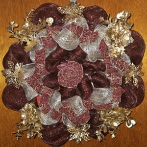 Handmade deep red and gold Christmas wreath with shimmering mesh ribbon, gold floral accents, and festive holiday design on a wooden door