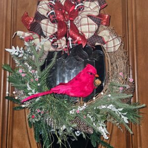 Handmade red cardinal Christmas wreath on grapevine base with evergreen foliage, pinecones, white berries, and a red glitter and plaid bow on a front door