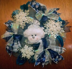 Handmade blue and white snowman winter wreath decorated with large sparkling snowflakes and layered winter ribbons.
