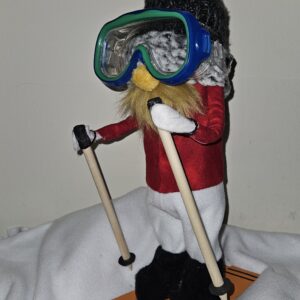 Side view of Bjorn Taski winter sports gnome holding ski poles with skis and cozy outfit