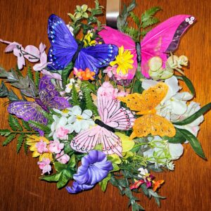 Handmade butterfly garden wreath with colorful purple, pink, blue, and gold butterflies surrounded by spring florals and greenery