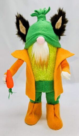 Handmade bunny gnome named Carrot wearing a green hat with tall bunny ears, orange coat, green outfit, and holding a bright orange carrot.