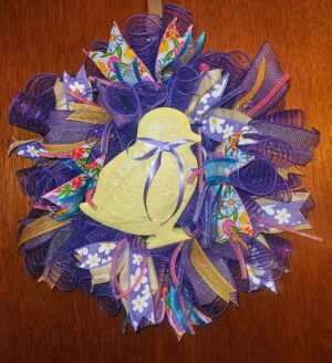 Welcome spring in cheerful style with this 20-inch Easter Chick Wreath. Designed in soft pastels and vibrant purples, this round wreath creates an eye-catching focal point for your front door, entryway, or interior wall. Layers of rich purple deco mesh form a full, lush base that gives this wreath beautiful volume and texture. Throughout the design, patterned ribbons in floral prints, daisies, gold accents, and soft pastel tones add depth and movement. Pops of pink, yellow, and blue bring the entire piece to life while keeping the look fresh and seasonal. At the center, an adorable yellow chick takes the spotlight. Finished with delicate glitter detailing and a soft lavender bow, the chick adds charm and personality without overwhelming the design. The combination of bold purple mesh and gentle spring colors makes this wreath stand out beautifully against neutral or brightly painted doors. Measuring approximately 20 inches round, this Easter Chick Wreath is perfectly sized to make a statement while still fitting standard doors comfortably. It works wonderfully for Easter celebrations, spring gatherings, church events, or simply welcoming guests with festive seasonal décor. Each wreath is carefully handcrafted with attention to detail and quality materials to ensure it holds its shape and beauty throughout the season. Hang it on your front door, above a mantel, or as part of your Easter decorating theme. Add a playful yet elegant touch to your home this spring with this vibrant 20-inch Easter Chick Wreath.