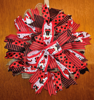 Handmade ladybug wreath with red and black polka dot ribbons, striped accents, and large decorative bow