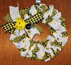 yellow and black bumble bee ribbon wreath with checkered ribbons, daisy bee ribbon, and metal bee accent