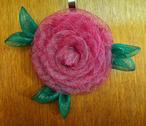Handmade fuchsia rose wreath with green leaves on wooden door