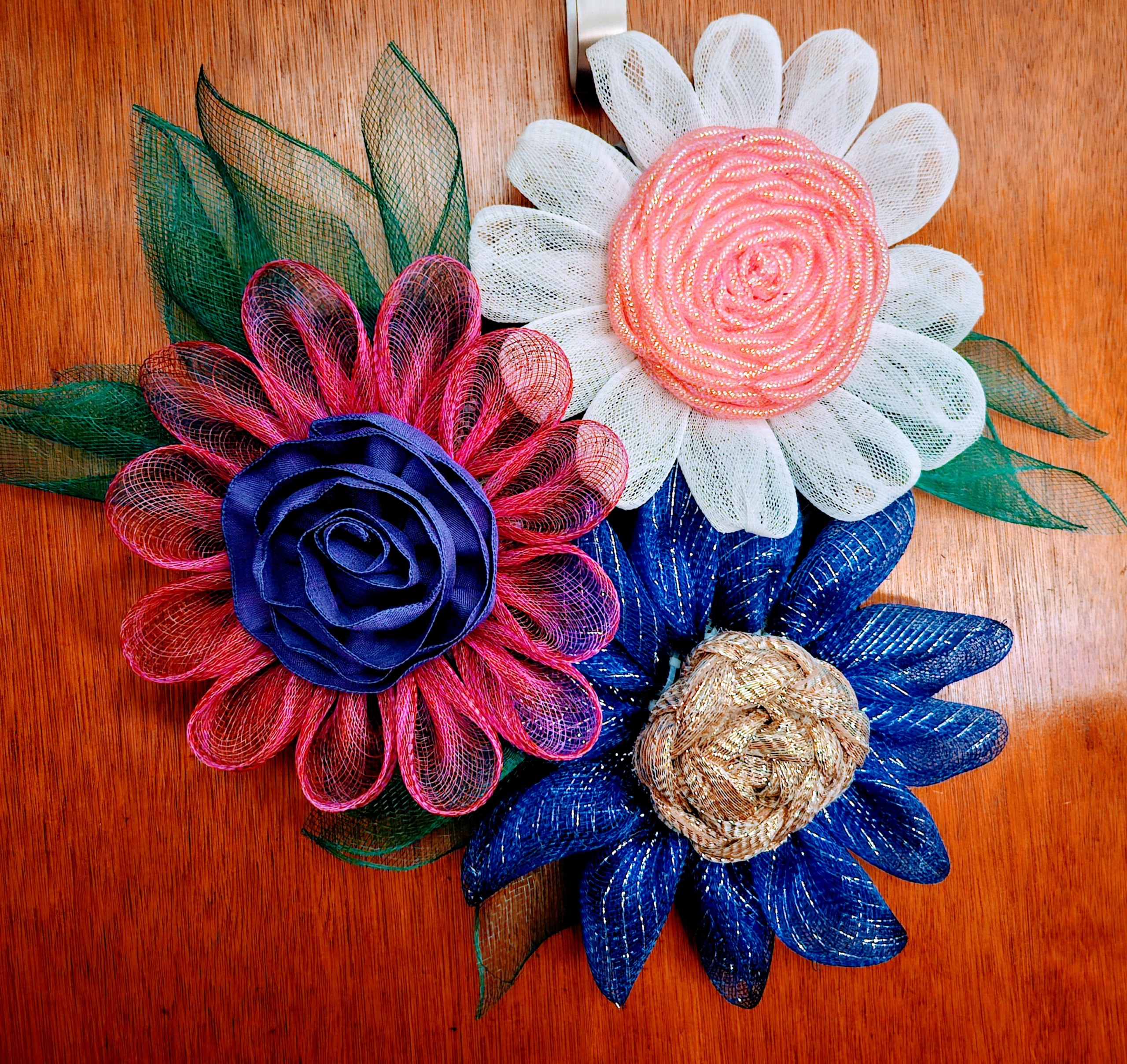Handmade pink, white and blue mesh flower wreath on wooden doo
