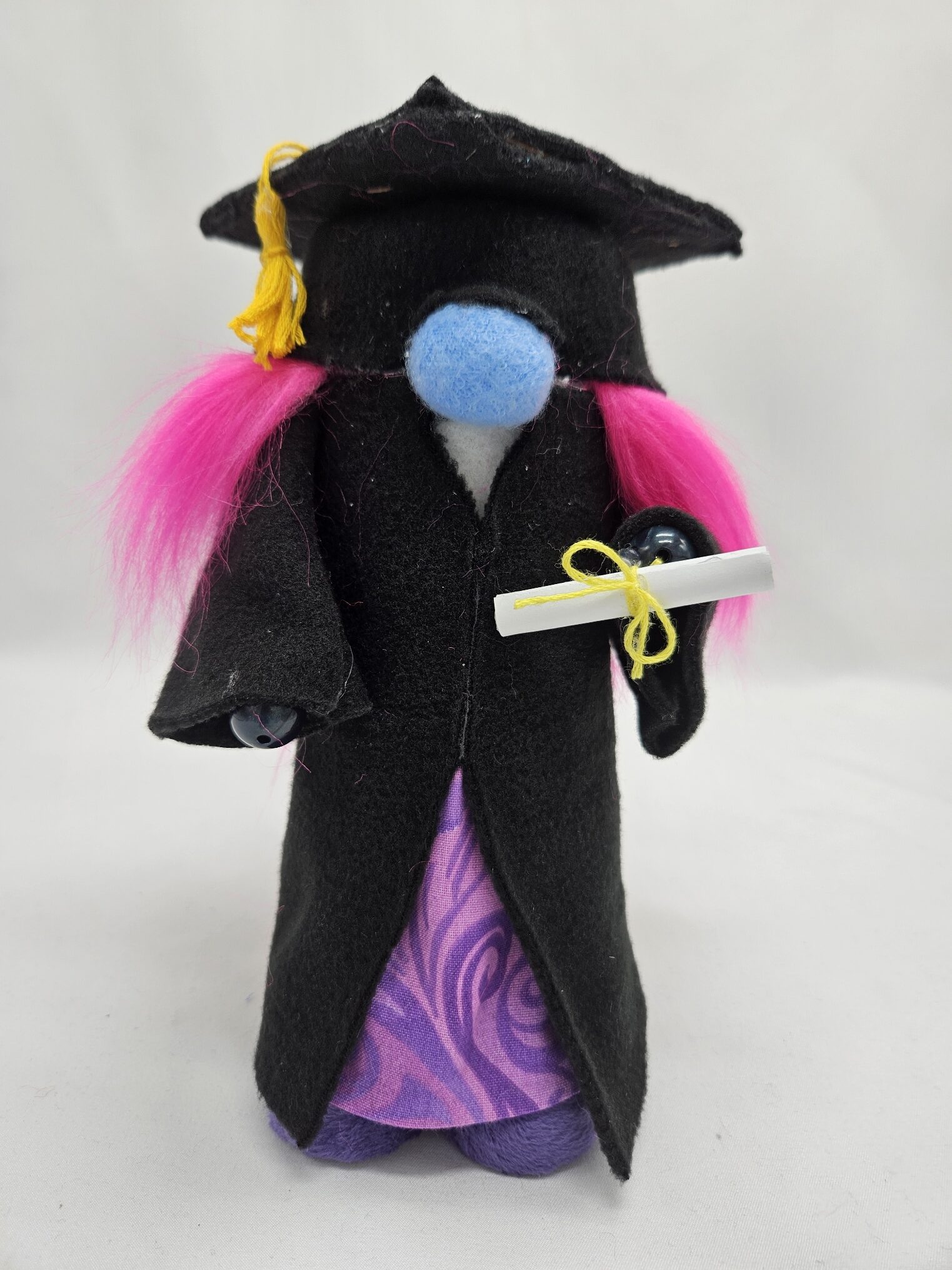 Handmade graduation gnome girl with pink hair, black robe, purple dress and diploma scroll